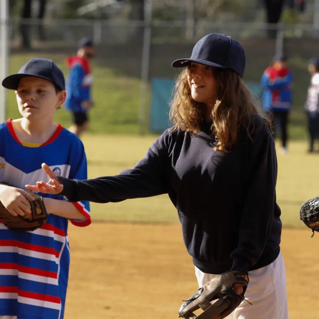 Female coach helping a child practise baseball at a 4titude school holiday sports session